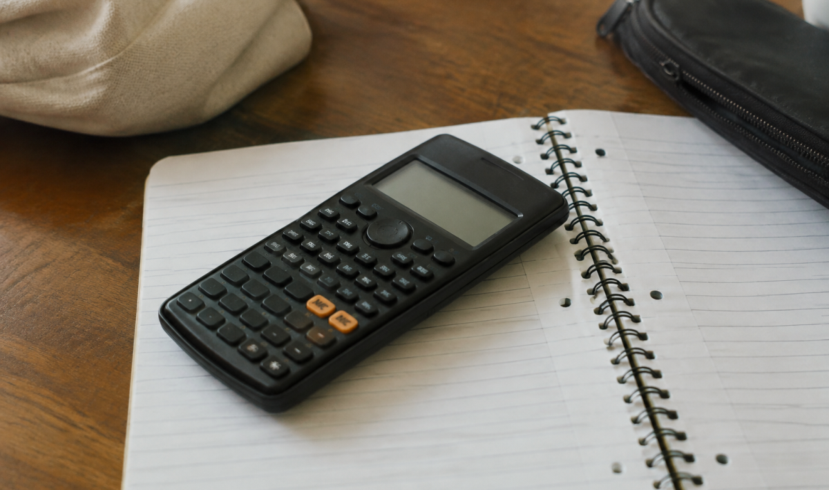 Calculatrice noire posee a plat sur un carnet ouvert