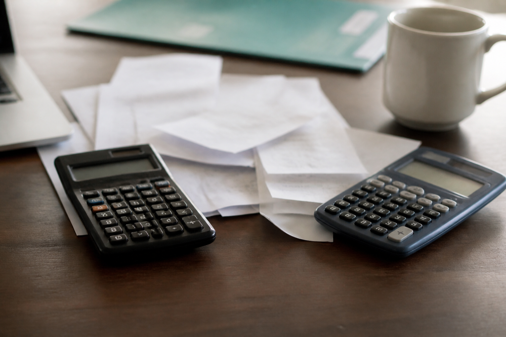 Deux calculatrices posees sur un bureau avec des factures