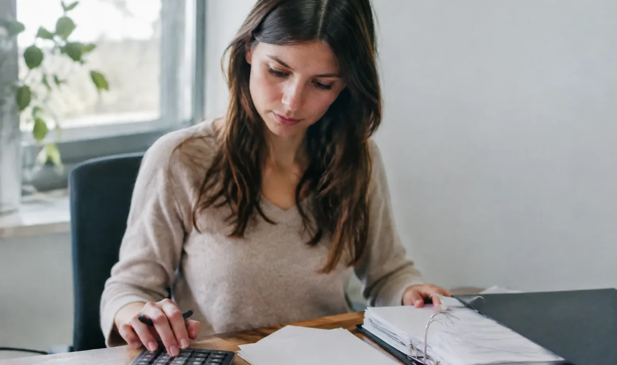 Femme assise au bureau avec calculatrice et classeur