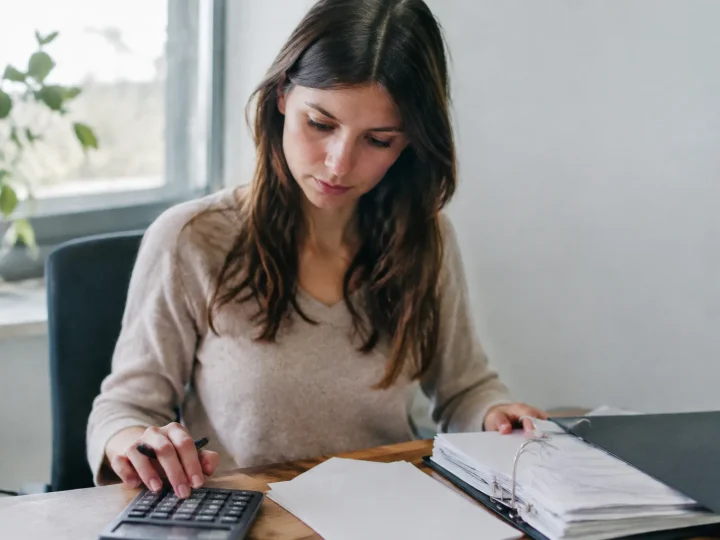 Femme assise au bureau avec calculatrice et classeur