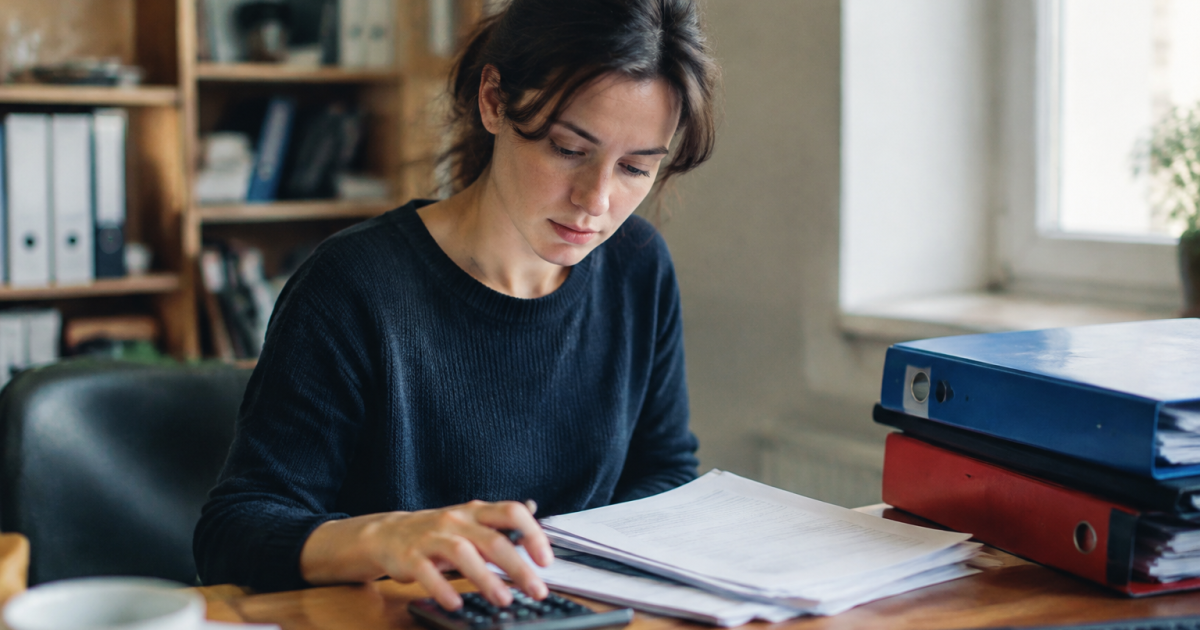 Femme assise devant un bureau avec calculatrice et classeurs
