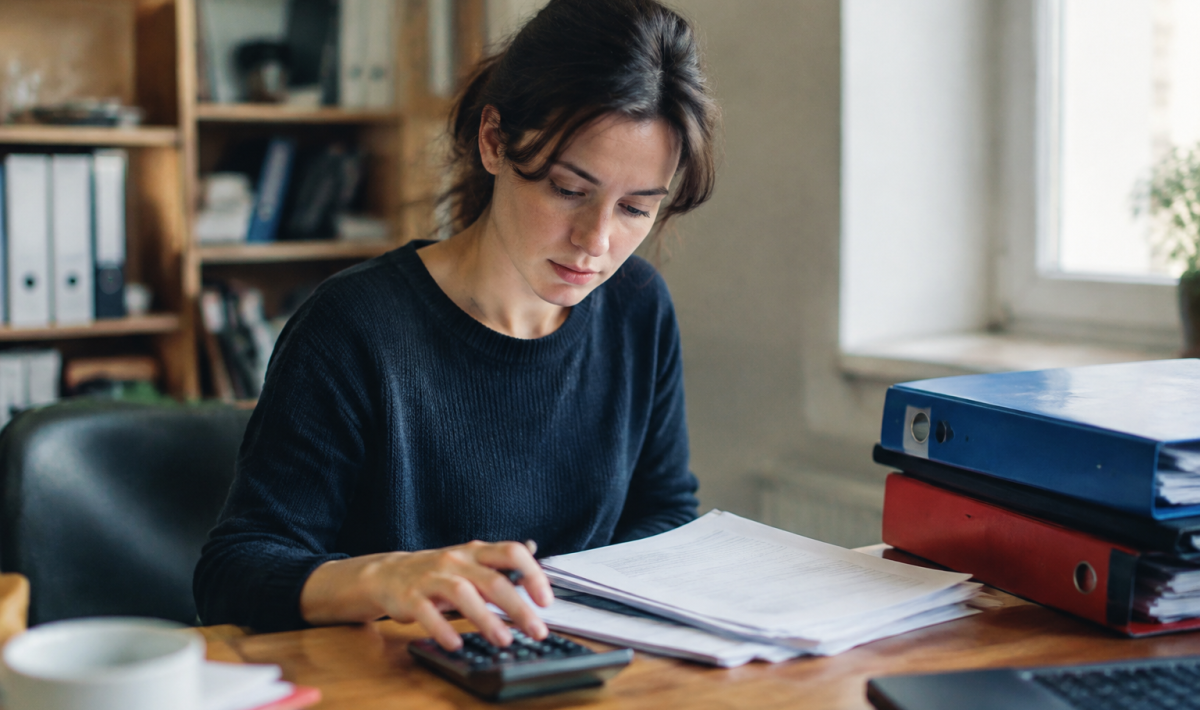 Femme assise devant un bureau avec calculatrice et classeurs