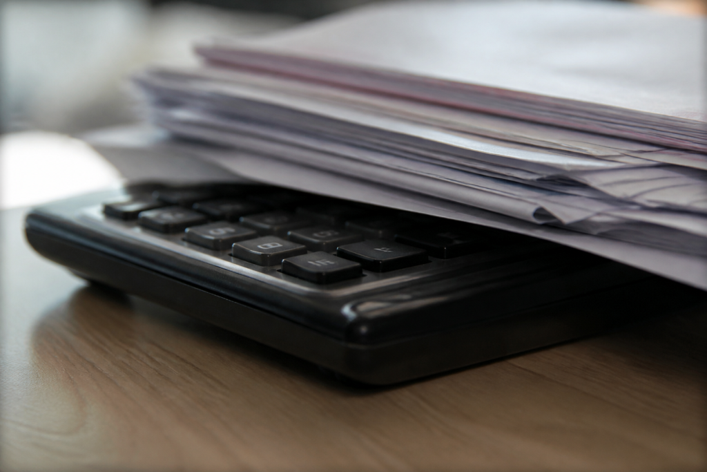 Fiches paie releves financiers empiles sur calculatrice noire