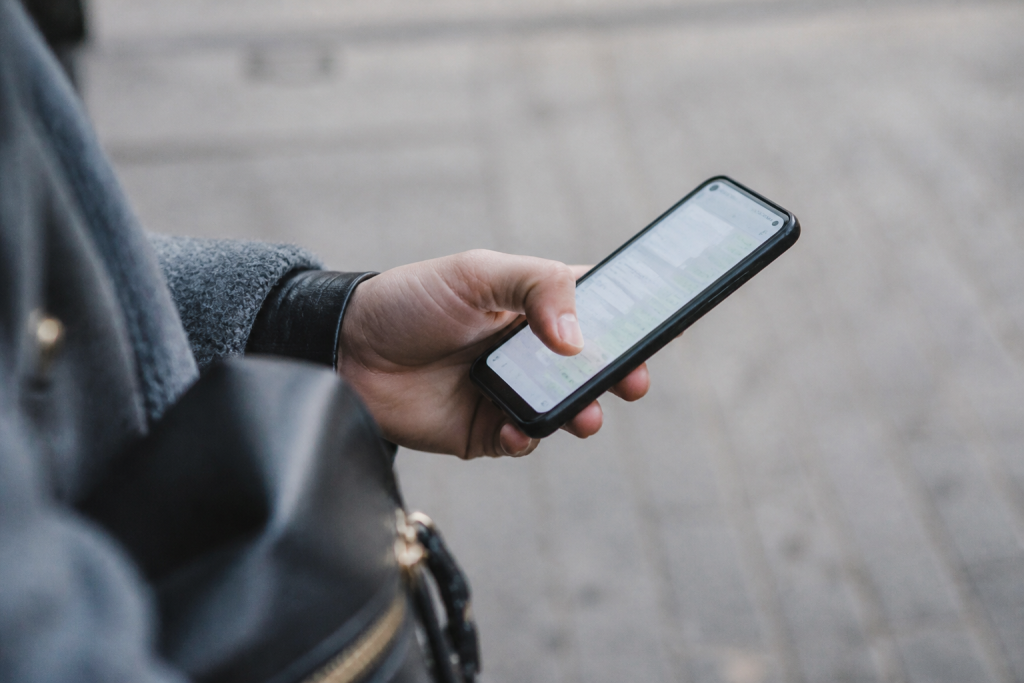 Main tenant un smartphone affichant une messagerie ouverte