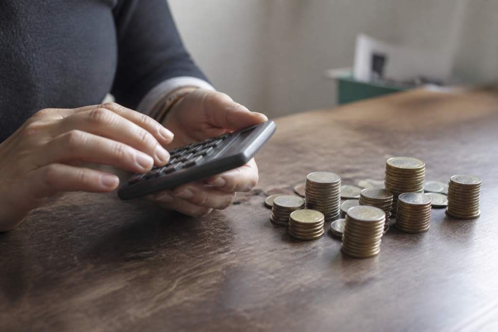 Mains tenant une calculatrice pres de piles de pieces