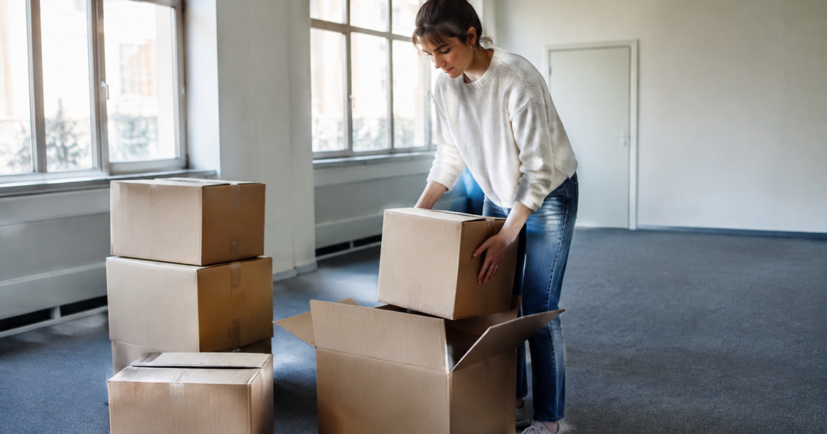 Personne debout range des cartons dans un bureau vide